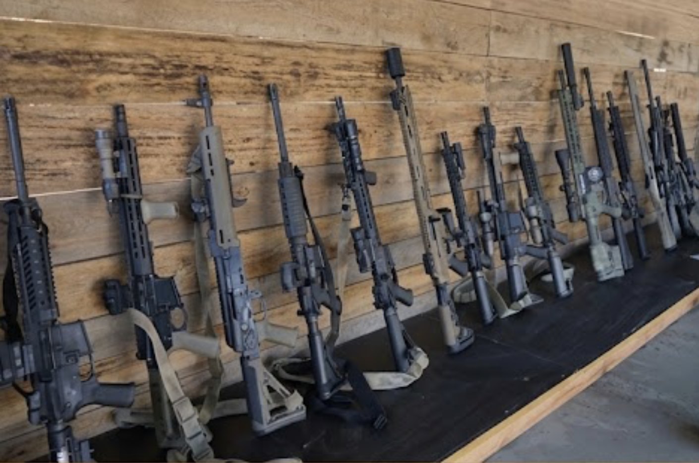 Reihe von Langwaffen an einer Holzwand auf einem Schießstand