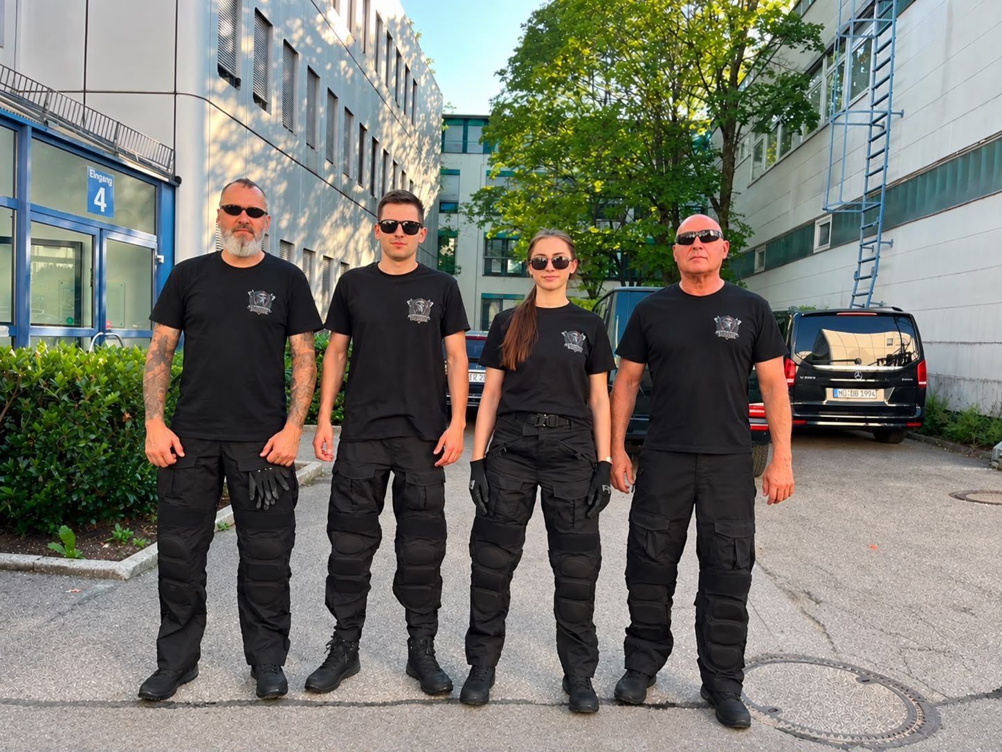 Vier Sicherheitskräfte von Scholder Security in schwarzer Dienstkleidung vor einem Firmengebäude